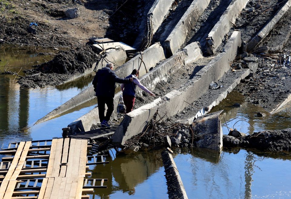 (10.14) Người dân Ukraine di chuyển trên một cây cầu bị đánh sập sau giao tranh giữa các lực lượng Nga và Ukraine tại Bakhmut. (Nguồn: Reuters)