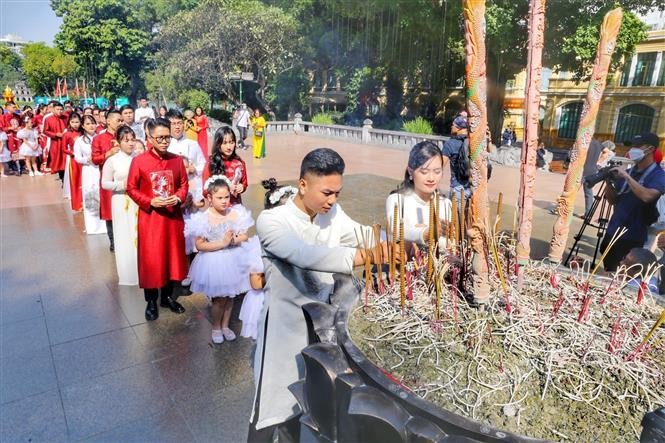 Các cặp đôi thực hiện nghi thức dâng hương tại Tượng đài Vua Lý Thái Tổ. Ảnh: Tuấn Đức - TTXVN