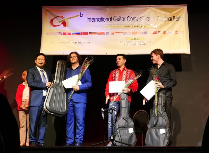 Giáo sư, nhạc sĩ Đặng Ngọc Long (bên trái) trao giải Nhất cho thí sinh đến từ Italy Luca Romanelli, giải Nhì cho thí sinh người Tây Ban Nha Samnuel Beluzan Rodriguez (áo đỏ) và thí sinh giải Ba đến từ Paraguay Raul Rolon. (Nguồn: TTXVN)