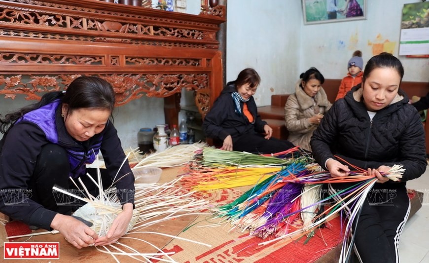 Nguyen Thi Dung (black top, centred) and her family have a long tradition of making Bodhi-leave-shaped fans. (Photo: VNP/VNA)