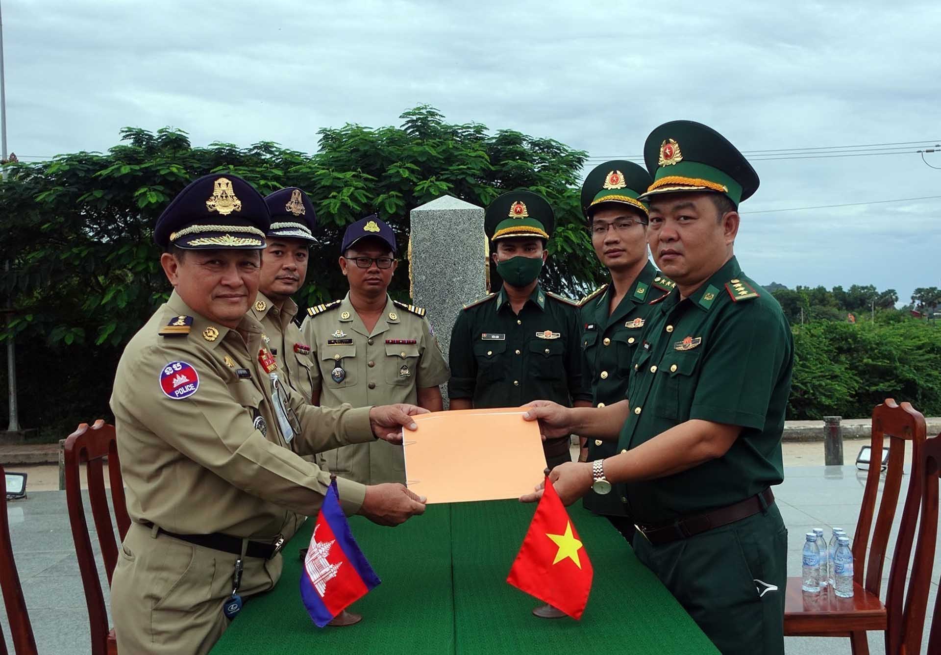 Đồn Biên phòng Cửa khẩu Quốc tế Hà Tiên và lực lượng chức năng Campuchia ký biên bản bàn giao tiếp nhận 67 công dân Việt Nam về nước. (Nguồn: TTXVN)