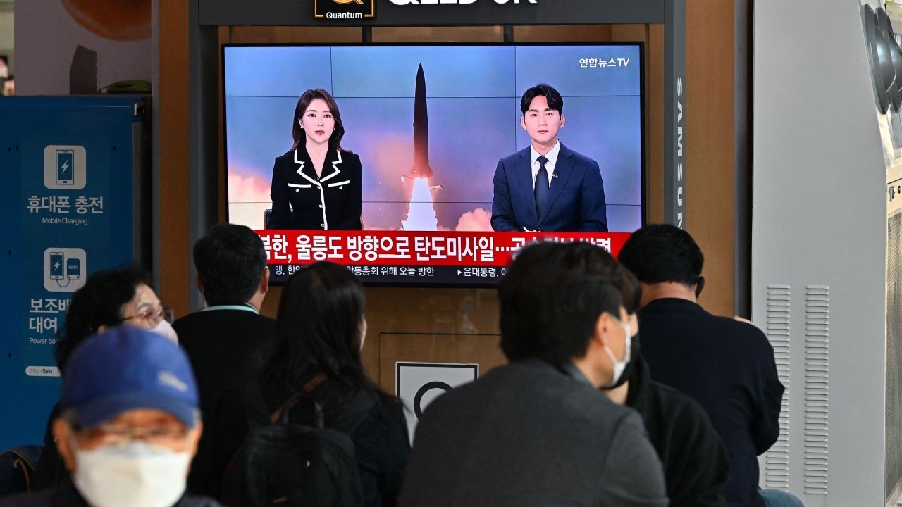 People watch a television screen showing a news broadcast with file footage of a North Korean missile test, at a railway station in Seoul on November 2, 2022. (Nguồn: CNN)