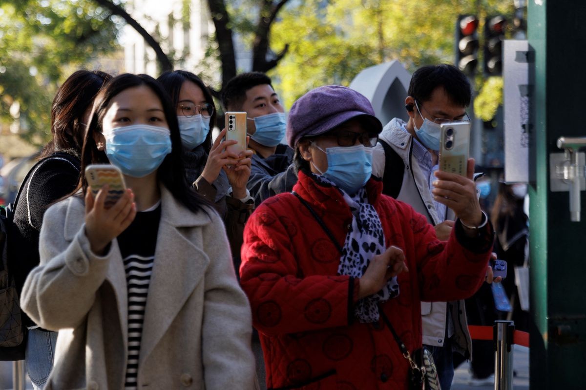 People scan their health codes before entering a fenced-off street as outbreaks of the coronavirus disease (COVID-19) continue in Beijing, China November 5, 2022. REUTERS/Thomas Peter