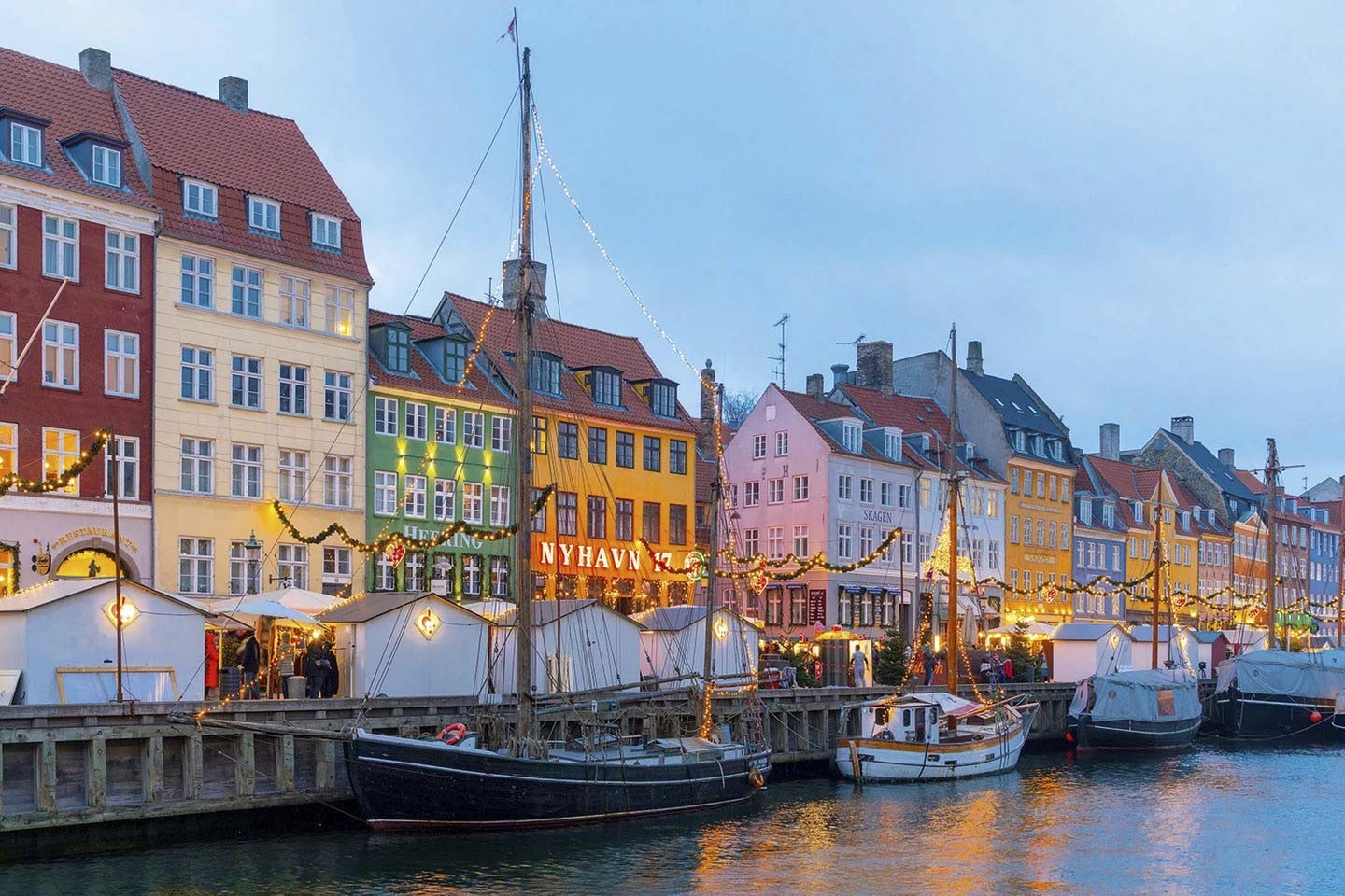 Copenhagen, Đan Mạch: Mùa đông đến, công viên giải trí lịch sử của Copenhagen, Tivoli Gardens, lấp lánh trong hàng triệu ánh đèn lễ hội. Các quầy hàng tràn ngập đồ chơi bằng gỗ, đồ trang trí bằng gốm truyền thống, rượu ngâm và Dansk aebleskiver (bánh rán 