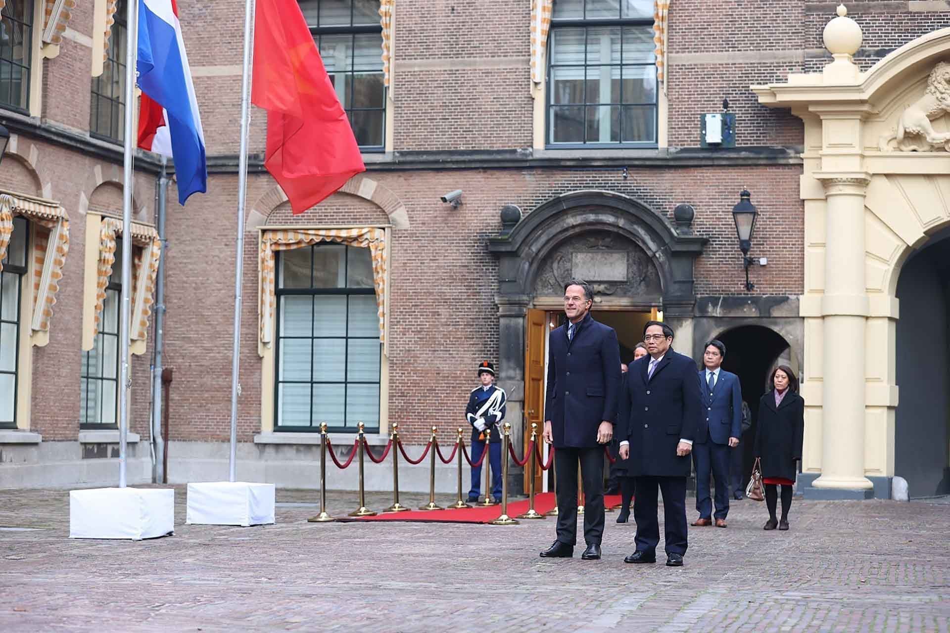 Thủ tướng Phạm Minh Chính và Thủ tướng Hà Lan Mark Rutte nghe quân nhạc cử quốc thiều hai nước. (Nguồn: TTXVN)
