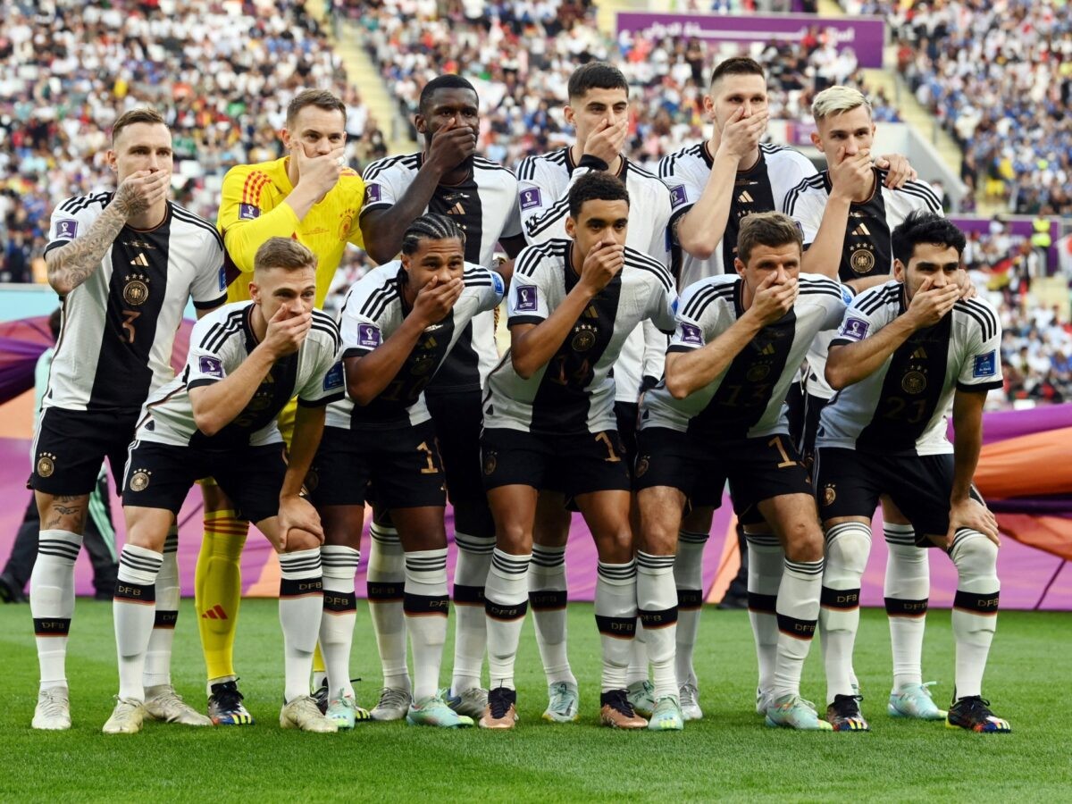 Các cầu thủ Đức che miệng khi họ chụp ảnh nhóm trước trận mở màn World Cup với Nhật Bản [Annegret Hilse/Reuters]
