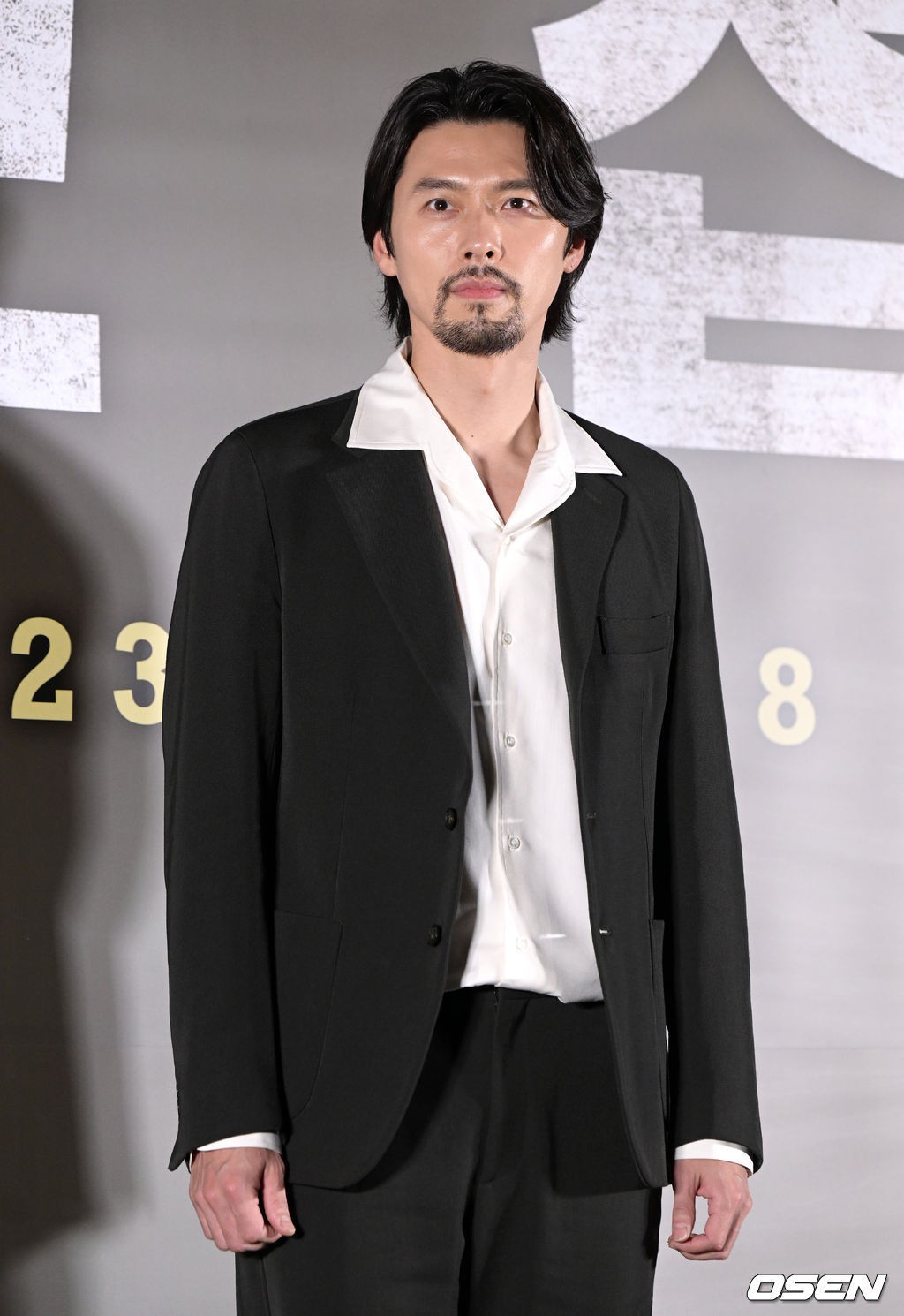 Hyun Bin để râu tóc phù hợp với tạo hình trong 'Negotiation' khi dự họp báo phim. Fan khen dù công việc vất vả, nhiều áp lực, diễn viên vẫn có làn da mịn không tì vết.