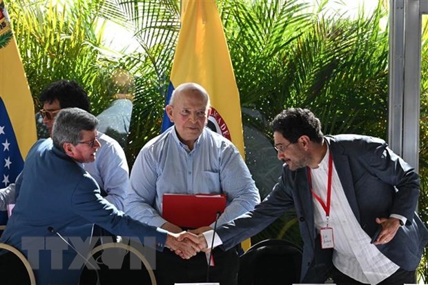 Trưởng đoàn đàm phán ELN Pablo Beltran (trái) và đại diện đoàn đàm phán của Chính phủ Ivan Cepeda (phải) trao đổi văn kiện thỏa thuận đạt được giữa hai bên tại vòng đàm phán ở Caracas, Venezuela ngày 12/12/2022.
