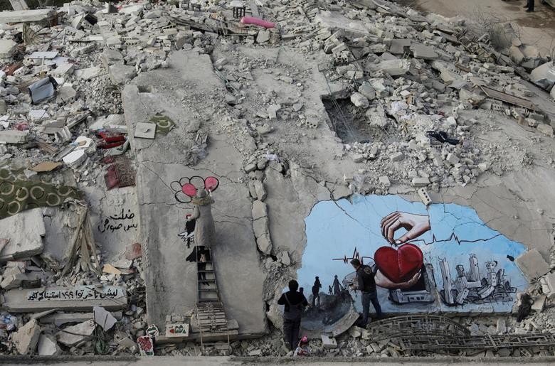 Các nghệ sĩ người Syria Aziz Asmar và Salam Hamed vẽ trên đống đổ nát của những tòa nhà bị hư hại sau trận động đất kinh hoàng hôm 6/2 tại thị trấn do quân nổi dậy kiểm soát Jandaris, Syria, ngày 22/2. (Nguồn: Reuters)