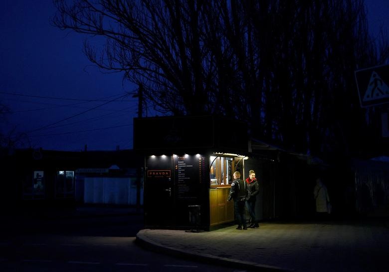 Mọi người đứng bên một quán cà phê ở Mykolaiv, Ukraine, ngày 19/2 vào lúc chạng vạng tối, trong thời gian khu vực này bị mất điện giữa bối cảnh xung đột với Nga vẫn diễn ra căng thẳng. (Nguồn: Reuters)
