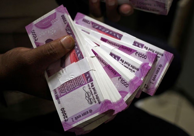 Một nhân viên ngân hàng ở Jammu (Ấn Độ) cầm các tập 2.000 rupee. Ảnh: Reuters