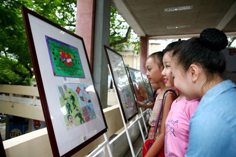 (05.19) Các em học sinh ngắm nhìn những bức ảnh tại Triển lãm tranh. (Ảnh: NVCC)
