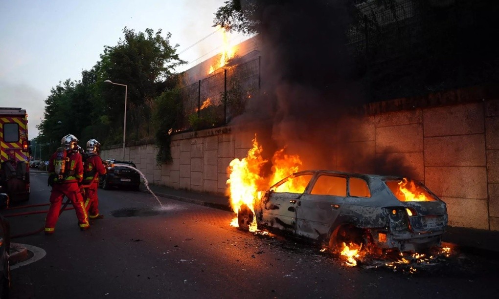 Lực lượng cứu hỏa dập lửa một chiếc ô tô đang bốc cháy do bạo loạn ở khu Nanterre, ngoại ô Paris, hôm 27/6. Ảnh: AFP