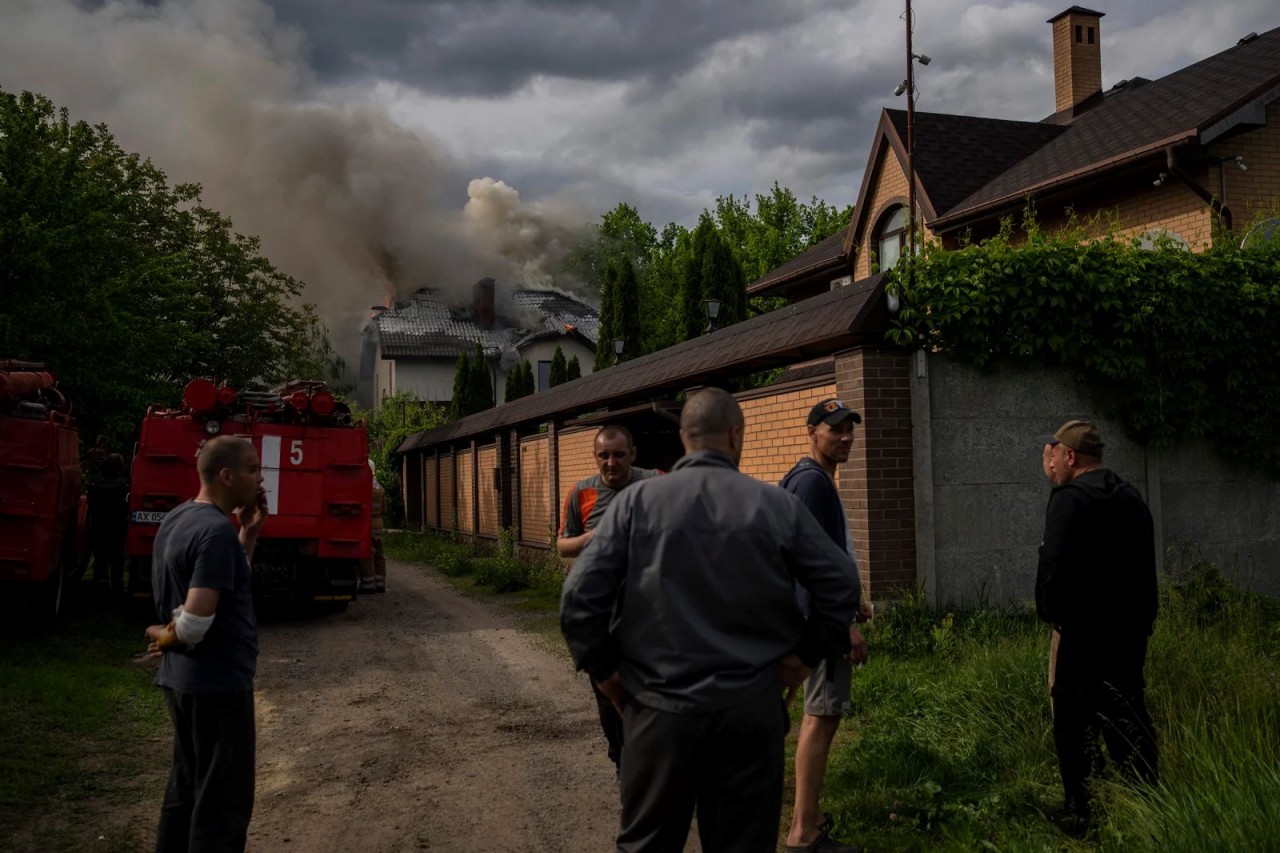 4.	Những người hàng xóm tụ tập quanh một ngôi nhà bốc cháy do bị trúng đạn chùm ở Kharkiv, Ukraine, vào ngày 30/5/2022. (Nguồn: API)