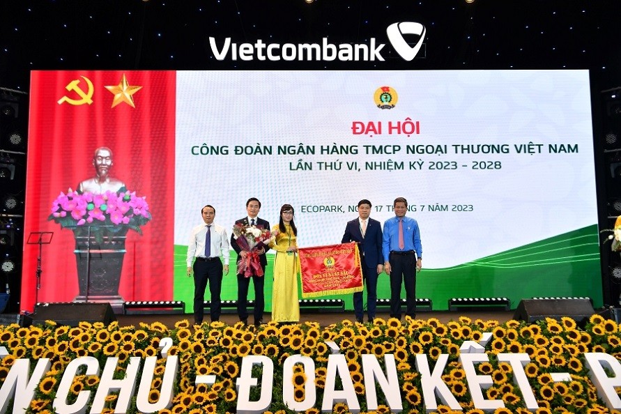 Đ/c Huỳnh Thanh Xuân – Phó Chủ tịch Tổng Liên đoàn Lao động Việt Nam (ngoài cùng bên phải) tặng Cờ Thi đua của Tổng Liên đoàn Lao động Việt Nam và đ/c Đỗ Việt Hùng – Phó Bí thư thường trực Đảng ủy Vietcombank (ngoài cùng bên trái) tặng hoa cho đại diện Công đoàn Vietcombank