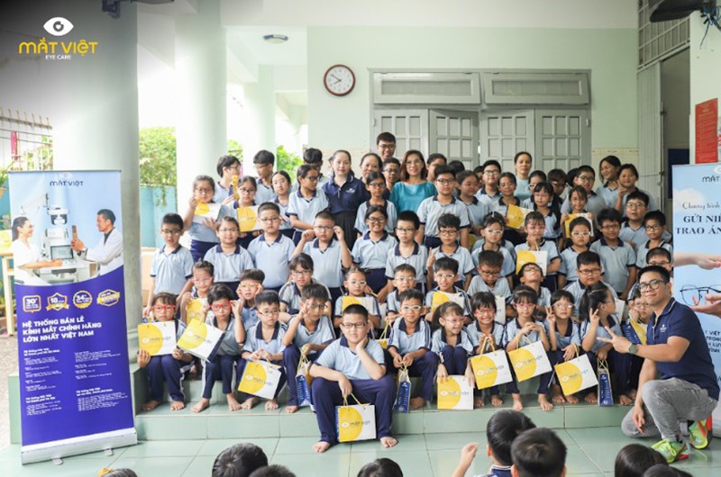 Chị Trần Vũ Phương Hà (áo xanh đeo kính đứng giữa) trong buổi trao tặng kính miễn phí cho quý cô và các em học sinh trường tình thương Ái Linh