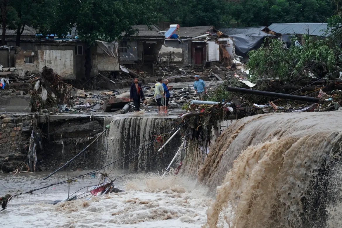 Dân làng tập trung gần những thiệt hại do nước lũ gây ra ở quận Mentougou, Bắc Kinh. [Andy Wong/Ảnh AP]