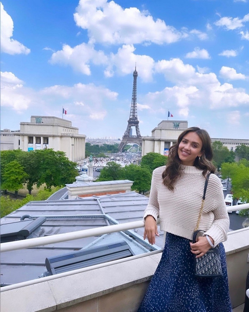 Trong chuyến dạo chơi Paris, Pháp, Jessica Alba phối áo len với chân váy họa tiết cánh hoa nhí và túi Dior. Ở đời thường hay khi du lịch, cô hướng tới gu mặc đơn giản, thoải mái để dễ di chuyển, làm việc.