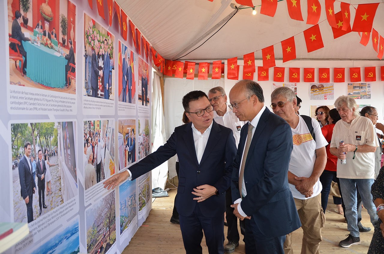 Tổng Biên tập Lê Quốc Minh và Đại sứ Đinh Toàn Thắng tham quan gian trưng bày của Báo Nhân Dân. (Nguồn: TTXVN)