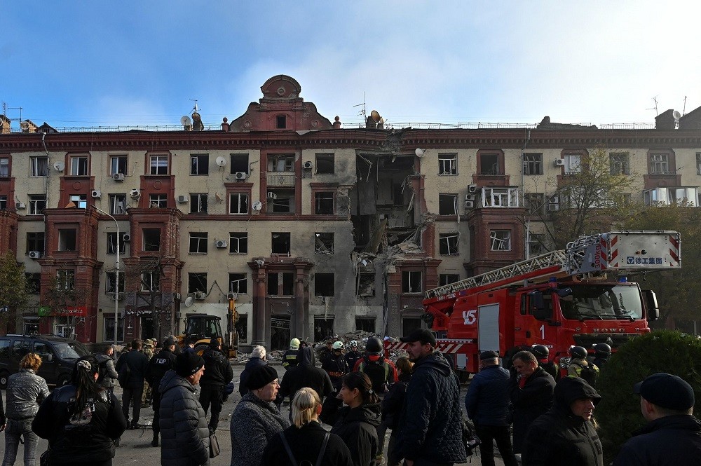 (10.19) Người dân Ukraine tụ tập trước tòa nhà bị hư hại sau đợt tấn công ở Zaporizhzhia, Ukraine. (Nguồn: Reuters)