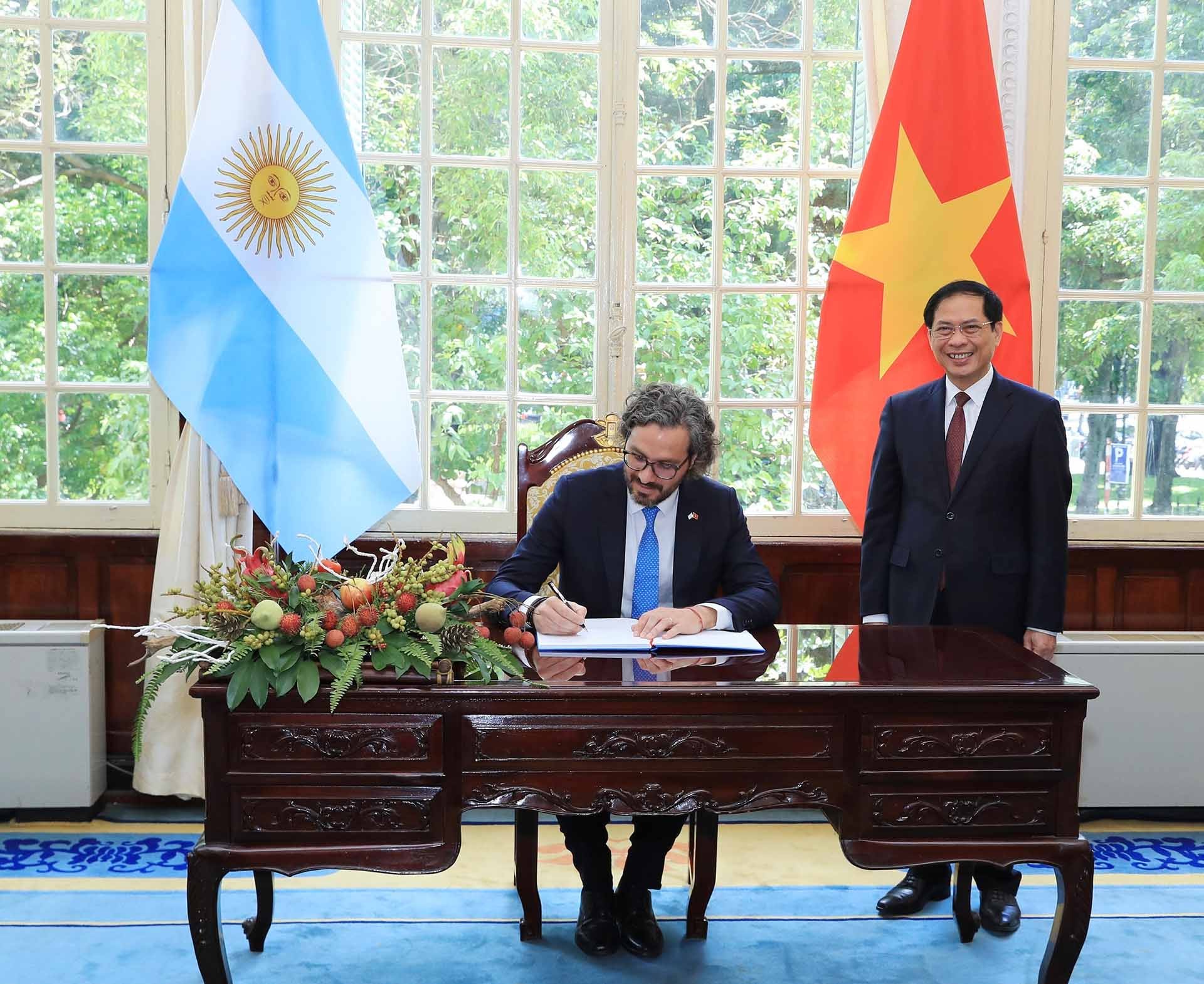 Bộ trưởng Ngoại giao Bùi Thanh Sơn chứng kiến Bộ trưởng Ngoại giao, Ngoại thương và Tôn giáo Argentina  Santiago Andres Cafiero ghi lưu bút trong chuyến thăm chính thức đến Việt Nam ngày 11/7/2022, tại Hà Nội. 