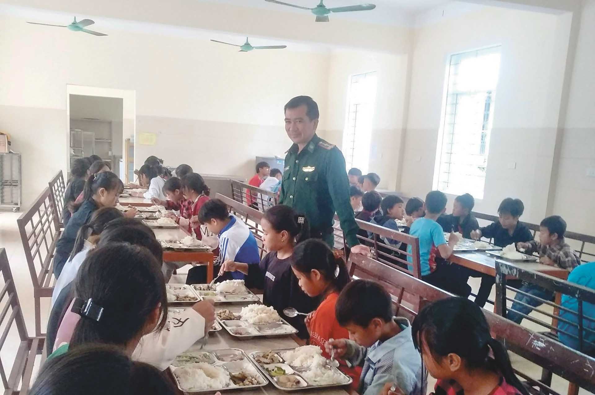 Thiếu tá Phan Văn Thắm chia sẻ bên mâm cơm của các em nội trú. (Ảnh: NVCC)