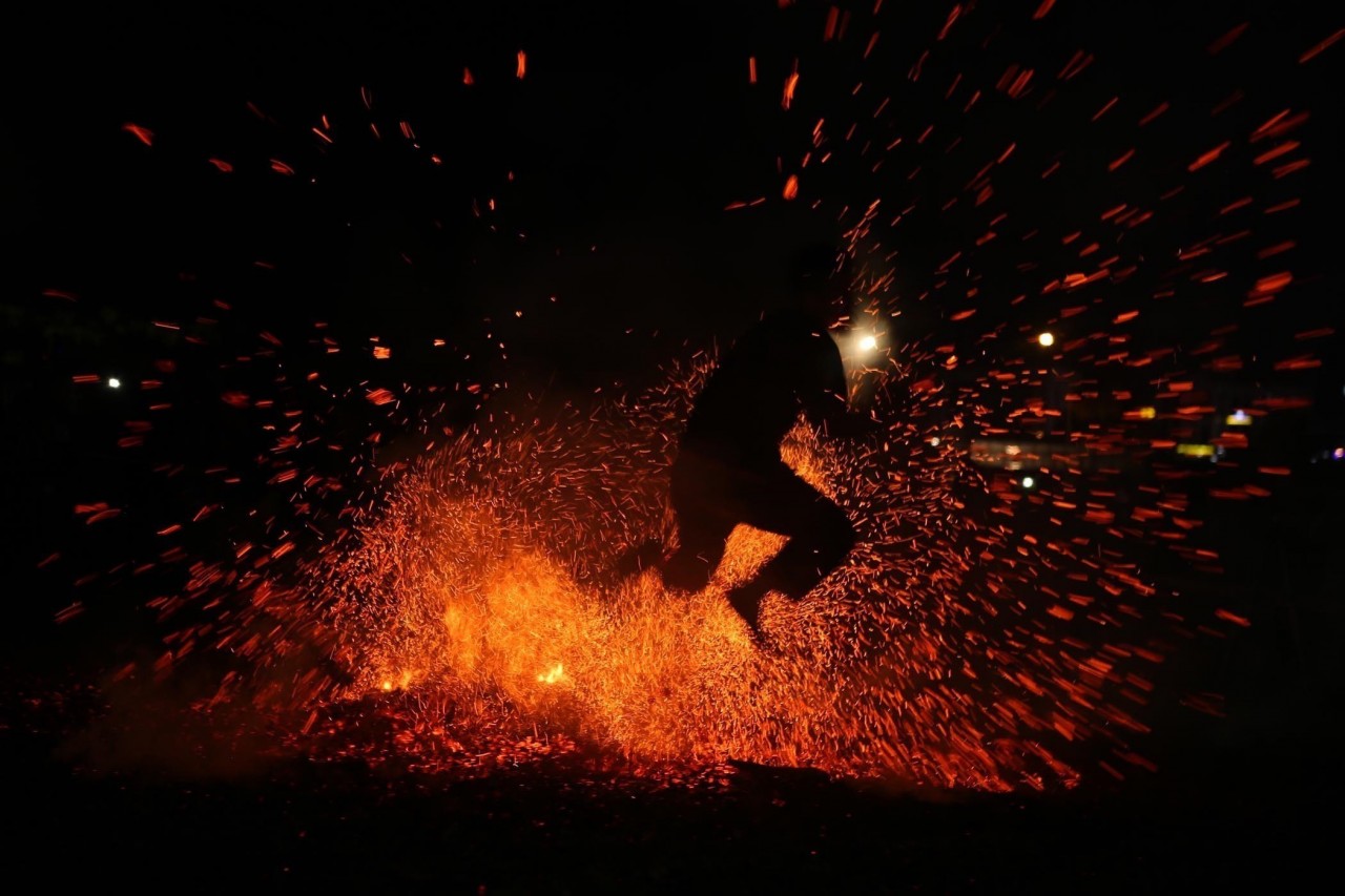 Những diễn viên sau khi được thầy cúng làm lễ nhập vai nhảy lửa, để dập tắt đống than đang cháy rực nhưng không bị bỏng. Ảnh: Quý Trung – TTXVN