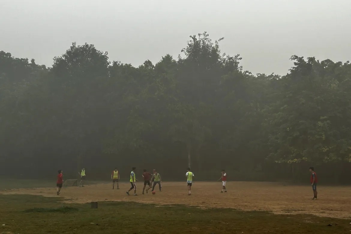 Trẻ em chơi bóng đá sớm trong một công viên được phủ sương mù ở New Delhi. [Rishi Lekhi/Ảnh AP]