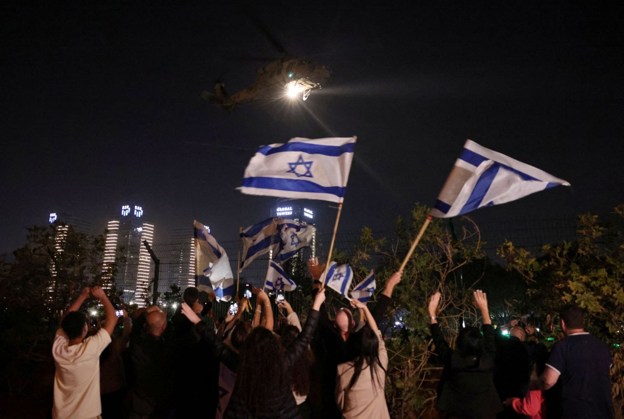 Người dân vẫy cờ Israel khi trực thăng chở con tin được Hamas thả tới Trung tâm y tế trẻ em Schneider ở Petah Tikva, Israel ngày 24/11. (Nguồn: Reuters)