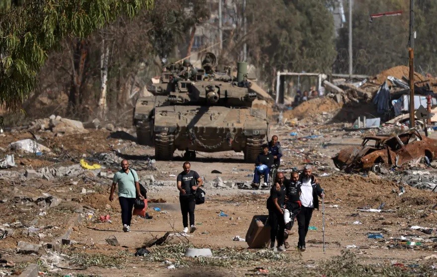 Người dân Palestine chạy trốn khỏi miền Bắc Gaza, đi ngang qua xe tăng của quân đội Israel, ngày 24/11 tại Dải Gaza. Tuần qua, Israel và Hamas đạt thỏa thuận ngừng bắn trong 4 ngày, bắt đầu từ 24/11. Theo đó, Israel ngừng chiến dịch trên không và trên bộ 