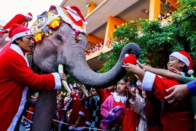 Học sinh chờ nhận quà từ một chú voi mặc trang phục ông già Noel tại trường học ở Ayutthaya, Thái Lan. (Nguồn: Reuters)