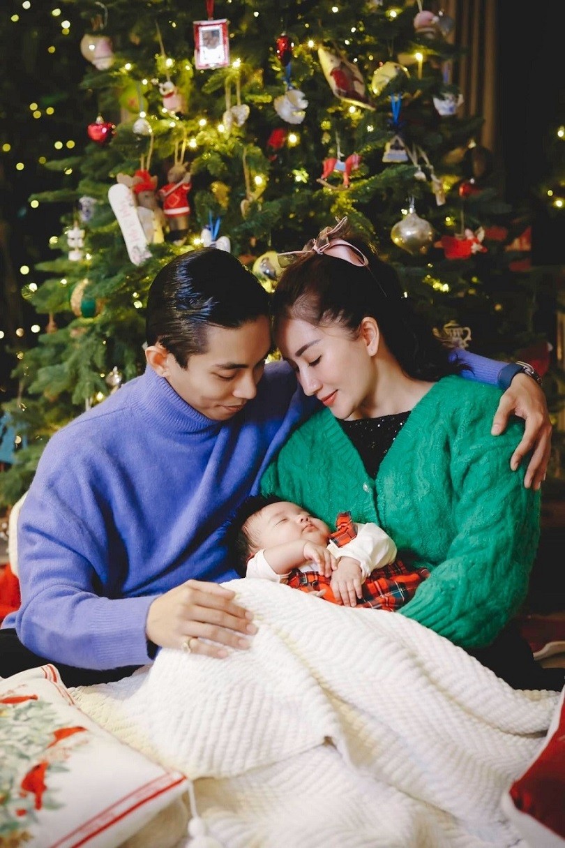 Khánh Thi - Phan Hiển diện áo len ấm áp, bế bé Lisa chụp ảnh Giáng sinh. Cặp vợ chồng chọn sắc xanh và tím đặc trưng mùa Noel để tạo sự ăn ý.