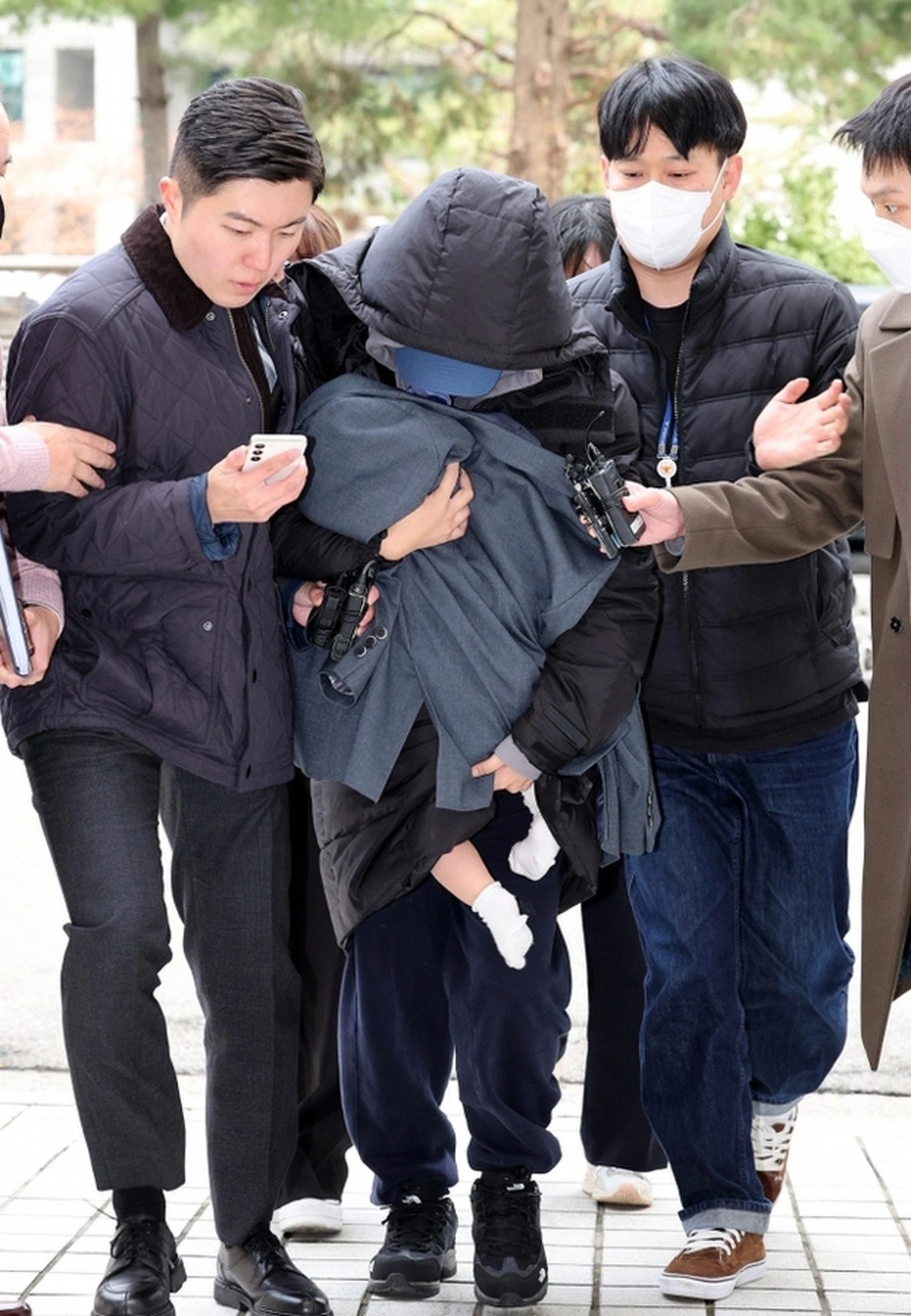 Người phụ nữ tên A bế theo một đứa trẻ khi bị cảnh sát bắt, ngày 28/12 (Ảnh: Chosun).
