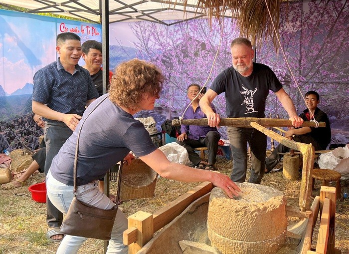 Foreign tourists enjoy participating in the experience of grinding corn with a stone mortar at the Hoa Ban Festival. (Photo: Dien Bien Phu newsapaper)