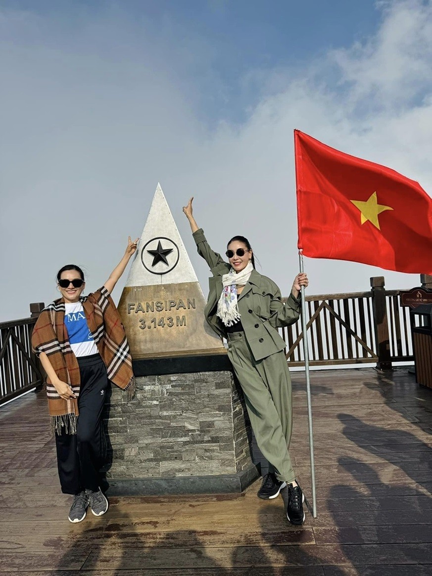 Hoa hậu Hà Kiều Anh cầm cờ Tổ quốc, chụp ảnh kỷ niệm cùng bạn thân Anh Thơ trên đỉnh Fansipan.