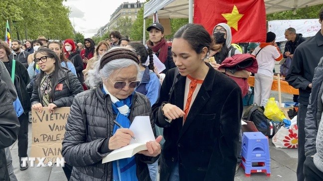 Bà Trần Tố Nga ký sách cho những người ủng hộ mình. (Ảnh: Thu Hà/TTXVN)
