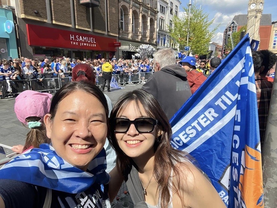 Asarapa chụp ảnh cùng con gái út Mooktapa trong lúc đợi xe bus chở các thành viên Leicester đi qua. Bà xã của Zico Thái cho biết, cô là fan của Leicester City 10 năm nay. Đội bóng này hiện do doanh nhân người Thái Lan Aiyawatt Srivaddhanaprabha làm Chủ tịch.