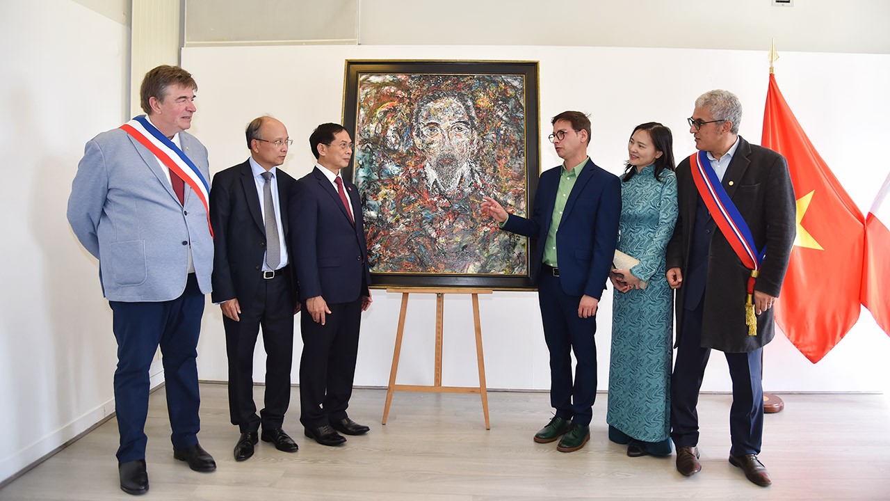 Bộ trưởng Bùi Thanh Sơn nghe họa sĩ gốc Romania giới thiệu bức chân dung Chủ tịch Hồ Chí Minh mang tên “Theo dấu chân Bác” lần đầu tiên được ra mắt công chúng.