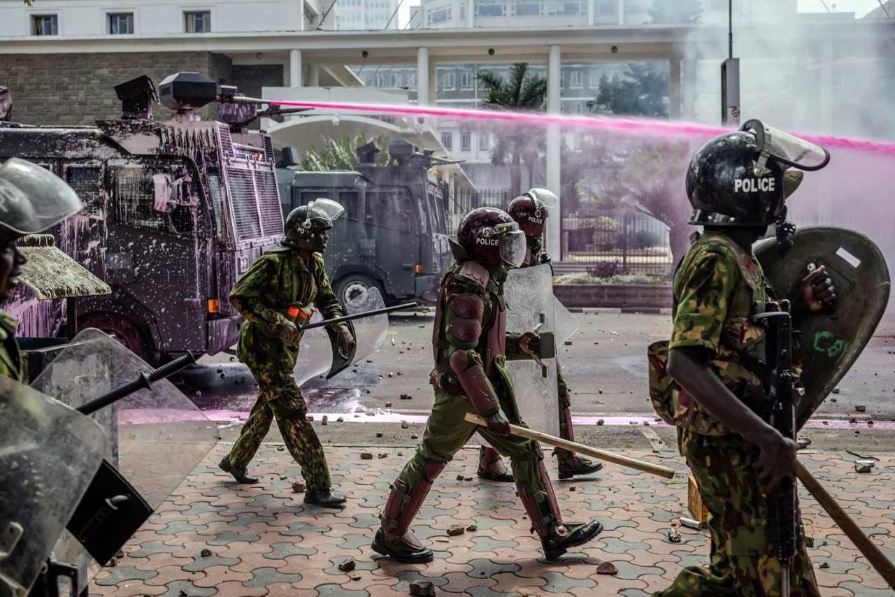 Các sĩ quan cảnh sát di chuyển theo đội hình bên cạnh xe phun nước màu khi họ đụng độ với những người biểu tình ở Nairobi, Kenya, ngày 25/6. Tuần qua, làn sóng biểu tình mới đã quét khắp quốc gia châu Phi này bất chấp việc Tổng thống William Ruto từ chối 