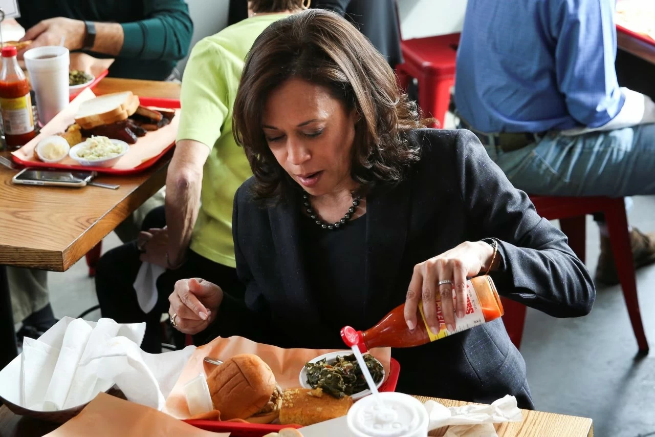 Thượng nghị sĩ và ứng cử viên tổng thống đảng Dân chủ Kamala Harris rưới nước sốt cay lên rau xanh khi ăn trưa tại Rodney Scott's BBQ ở Charleston, Nam Carolina, tháng 2 năm 2019. REUTERS