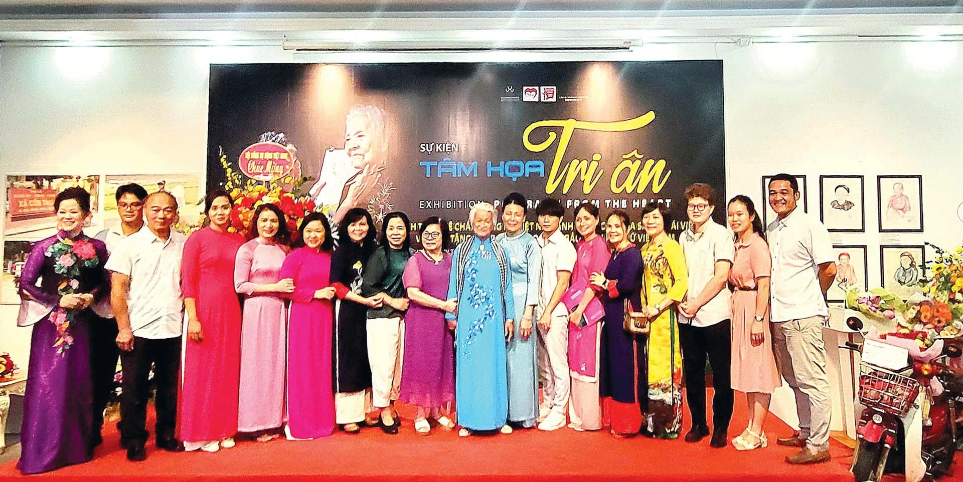 Họa sĩ Đặng Ái Việt mặc áo dài màu xanh (ở giữa) chụp ảnh kỷ niệm với các đại biểu đến dự sự kiện.  (Ảnh: George Newman)