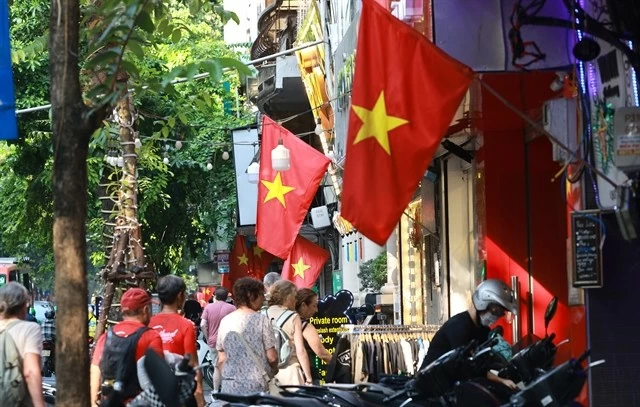 Tourists pass by Hang Bong Street in Hanoi. Every streets and roads of the city are brightly decorated with flags, flowers, hoardings, posters, and banners associated with historical images to welcome the national holidays. (Photo: VNA/VNS)