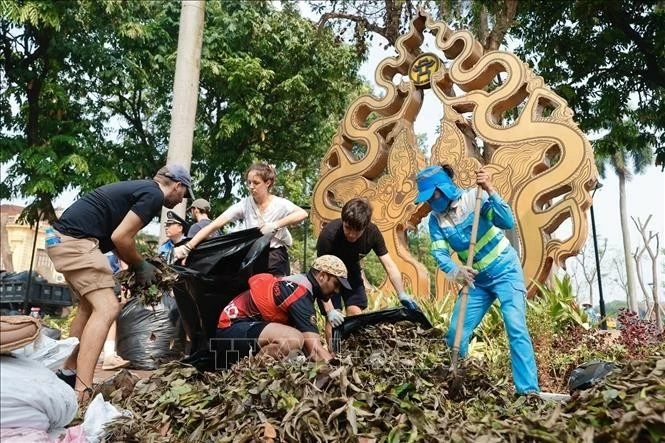 Tình nguyện viên nước ngoài chung tay cùng người dân Thủ đô làm vệ sinh môi trường, khắc phục hậu quả bão số 3. Ảnh: Minh Quyết - TTXVN