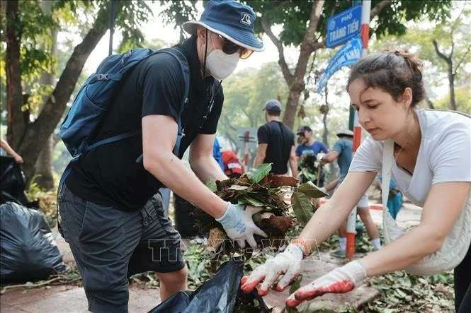 Tình nguyện viên cùng chung tay dọn dẹp, vệ sinh môi trường, khắc phục hậu quả bão số 3 tại khu vực quận Hoàn Kiếm. Ảnh: Minh Quyết - TTXVN