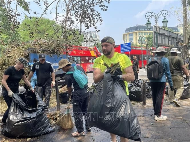 Tình nguyện viên chung tay dọn dẹp vệ sinh khu vực cạnh Quảng trường Cách mạng tháng Tám. Ảnh: Minh Quyết - TTXVN