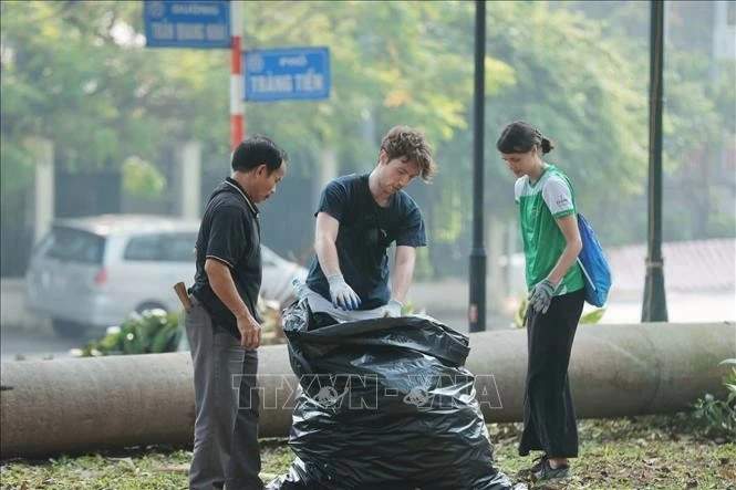 Tình nguyện viên thu gom rác tại khu vực vườn hoa Bác Cổ (quận Hoàn Kiếm). Ảnh: Minh Quyết - TTXVN