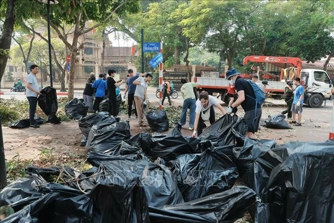 Tình nguyện viên cùng tham gia thu gom rác tại khu vực vườn hoa Bác Cổ (quận Hoàn Kiếm). Ảnh: Minh Quyết - TTXVN