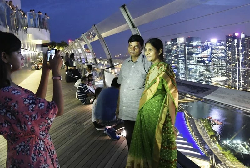 Khách du lịch tạo dáng chụp ảnh trên đài quan sát của Marina Bay Sands ở Singapore. Ảnh: Kyodo News Stills qua Getty Images