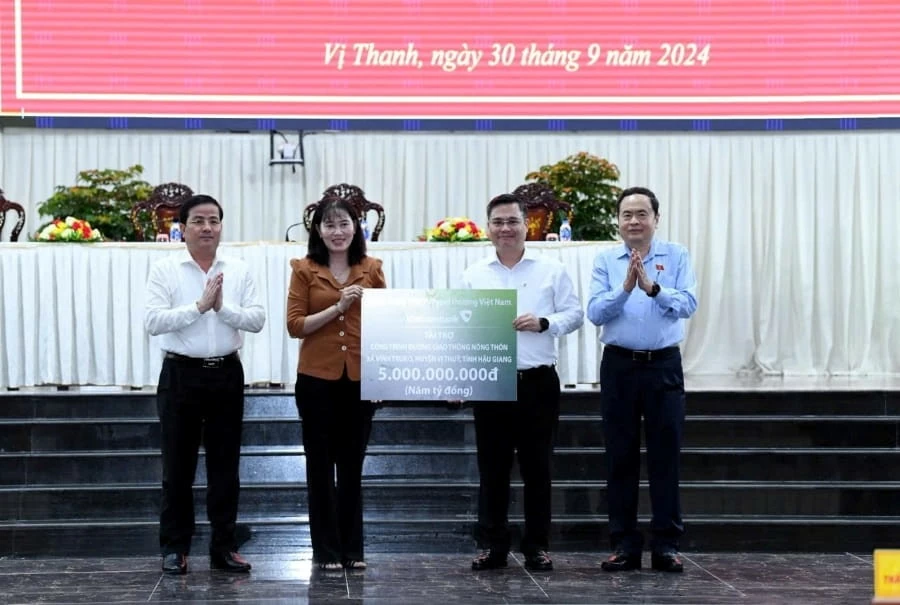 Đại diện Vietcombank, ông Nguyễn Thanh Tùng - Chủ tịch HĐQT Vietcombank (thứ 2 từ phải sang) trao biển tài trợ công trình đường giao thông nông thôn xã Vĩnh Trung, huyện Vị Thủy, tỉnh Hậu Giang cho đại diện tỉnh Hậu Giang, bà Hồ Thu Ánh - Bí thư Huyện ủy 