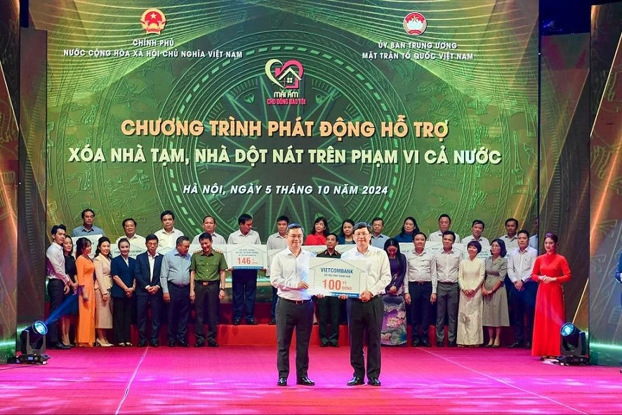 Ông Nguyễn Thanh Tùng (bên trái) - Bí thư Đảng uỷ, Chủ tịch HĐQT Vietcombank trao bảng tượng trưng kinh phí 100 tỷ đồng hỗ trợ xoá nhà tạm, nhà dột nát ủng hộ cho đại diện địa phương